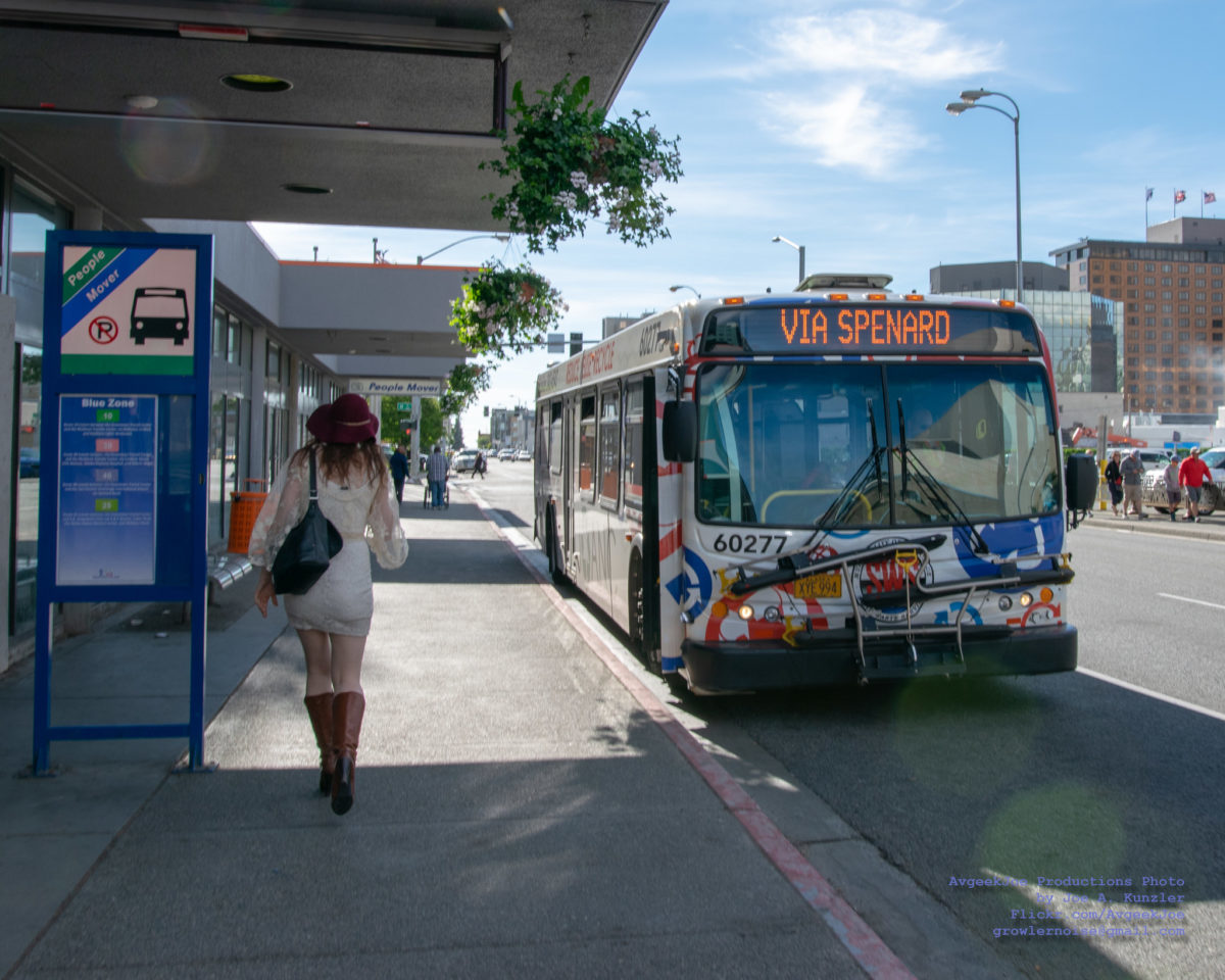 Woman walking by a bus stop in Anchorage, Alaska. The bus is stopped to pick up passengers.