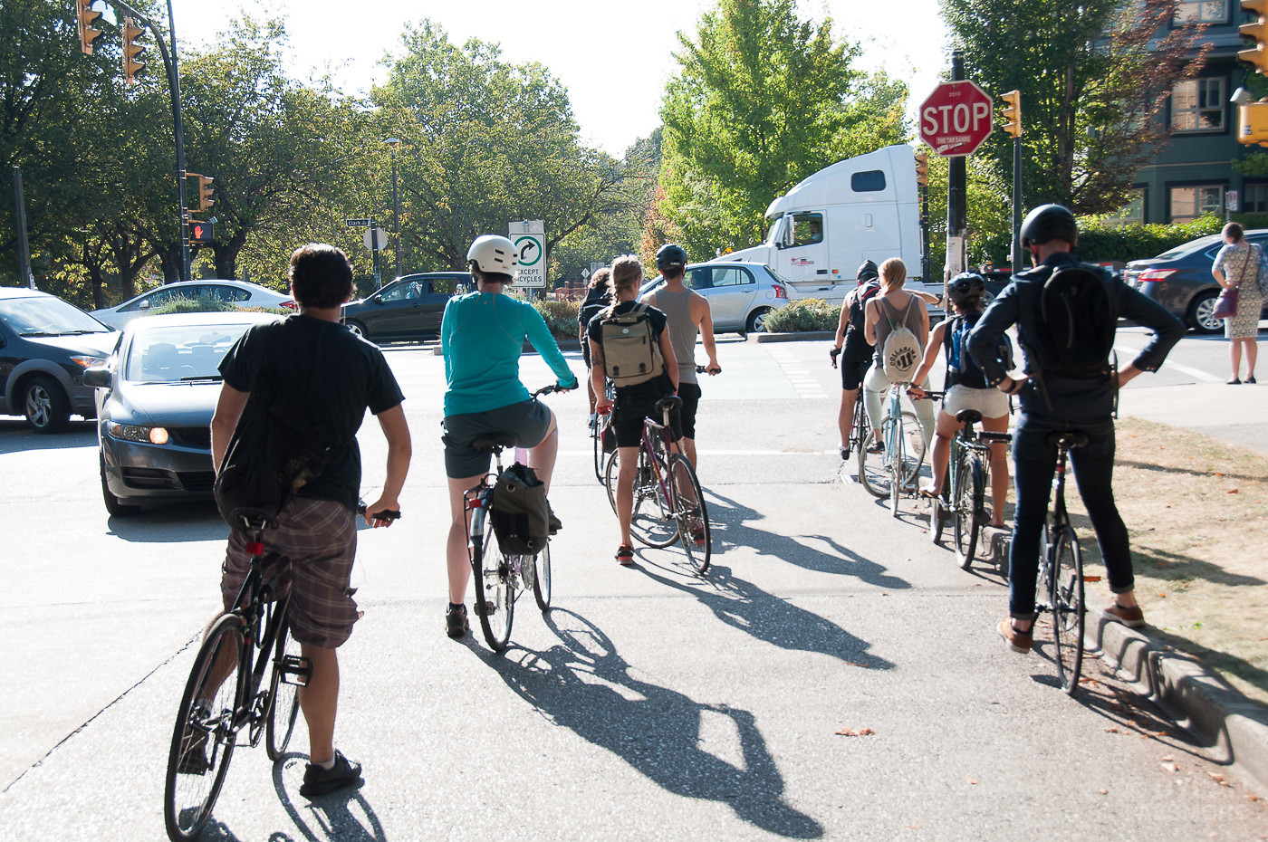 People on bikes waiting at a stop sign to cross a congested intersection