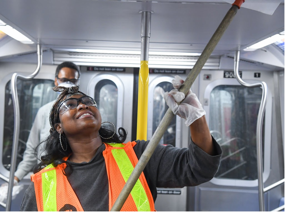 woman in MTA subway carriage cleaning the ceiling