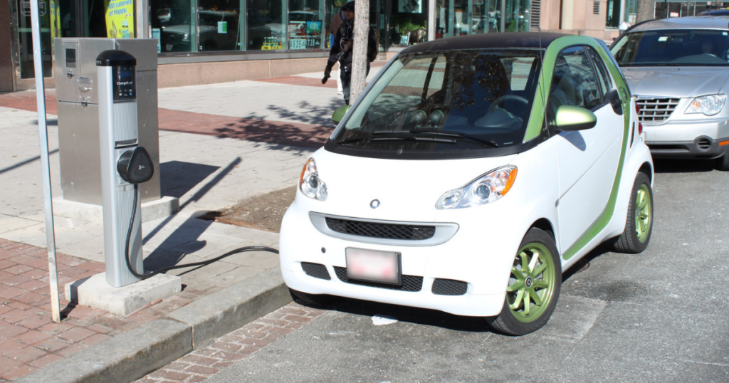 An electric Smart car charges at a curbside charging station in DC