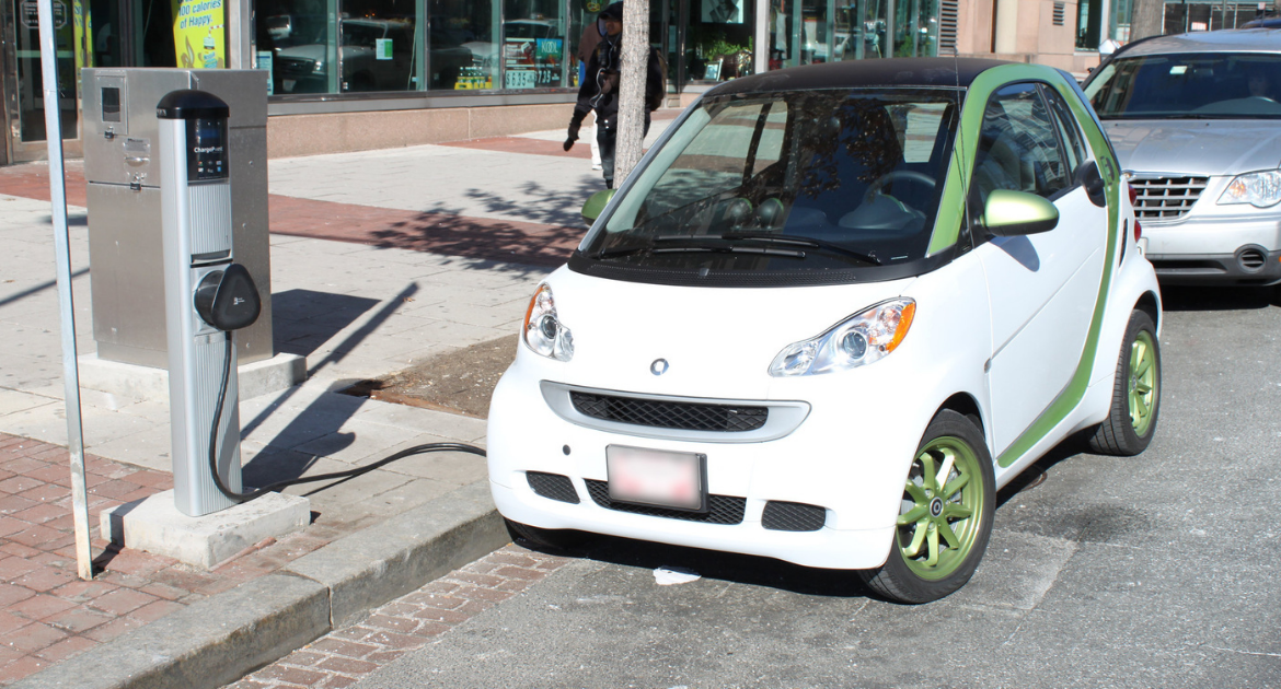 An electric Smart car charges at a curbside charging station in DC