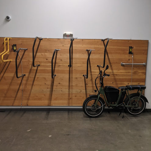 A heavy bike sits to the side next to a hanging bike rack