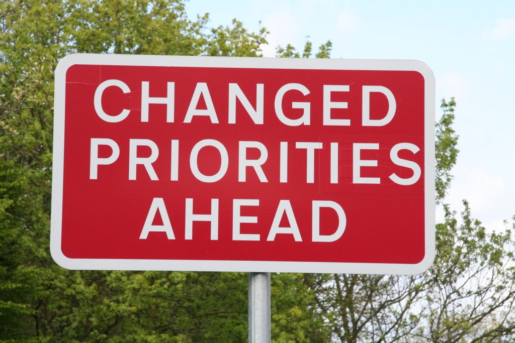 road sign that says "changed priorities ahead"