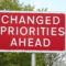 road sign that says "changed priorities ahead"