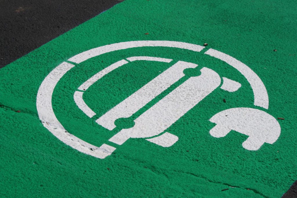A parking space painted green with a symbol indicating the space is dedicated for EVs