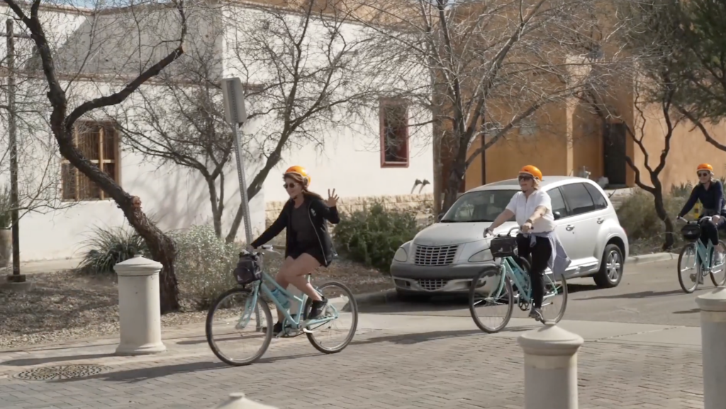 three cyclists ride their bikes down a tucson street