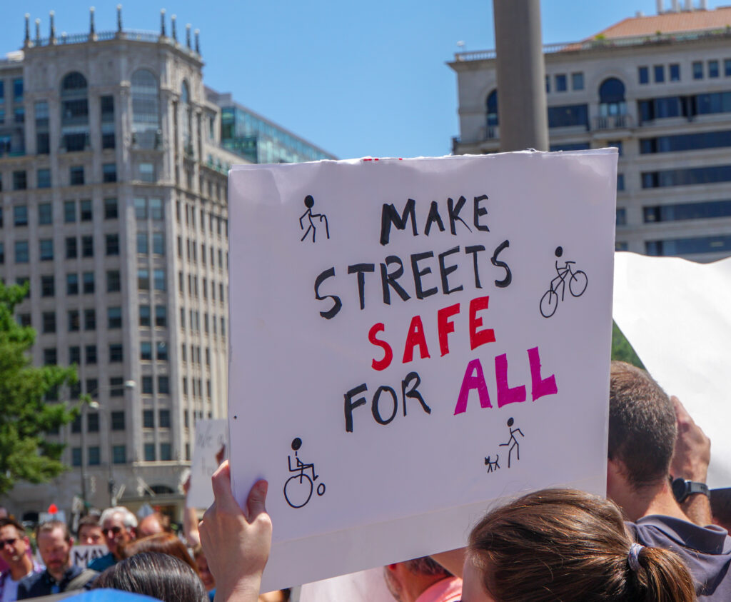 Activist holding a sign that says "Make streets safe for all"