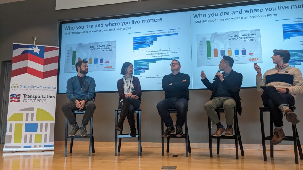 five panelists on stage discussing data in front of big screens