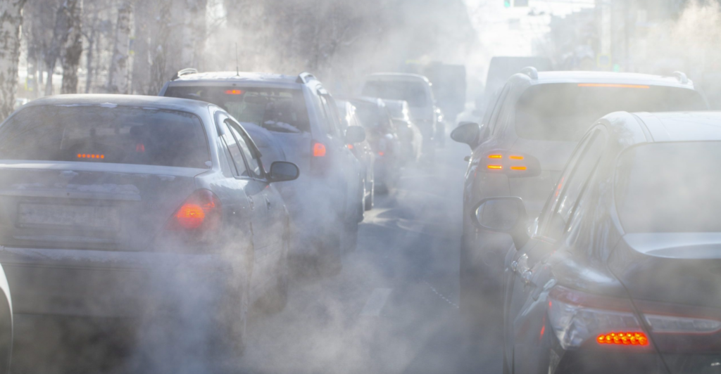 A cloudy haze of smoke surrounds back-to-back vehicles in stand-still traffic
