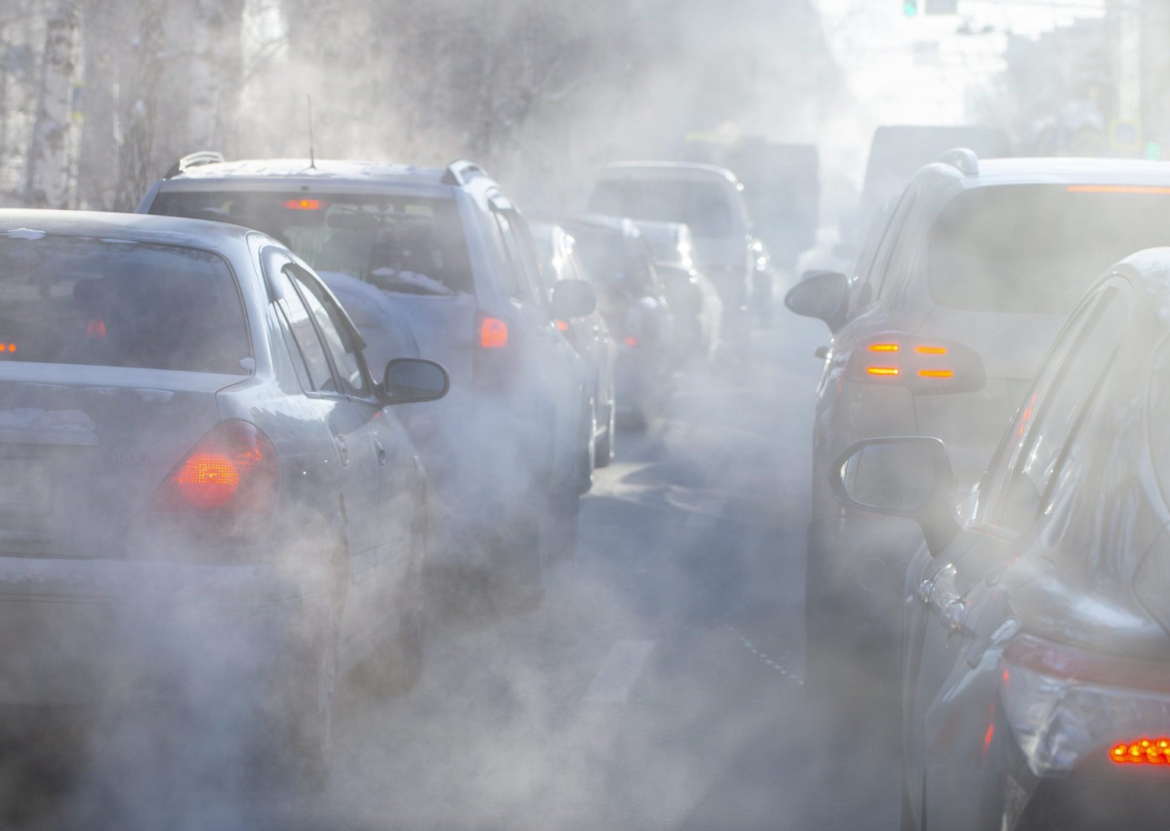 A cloudy haze of smoke surrounds back-to-back vehicles in stand-still traffic