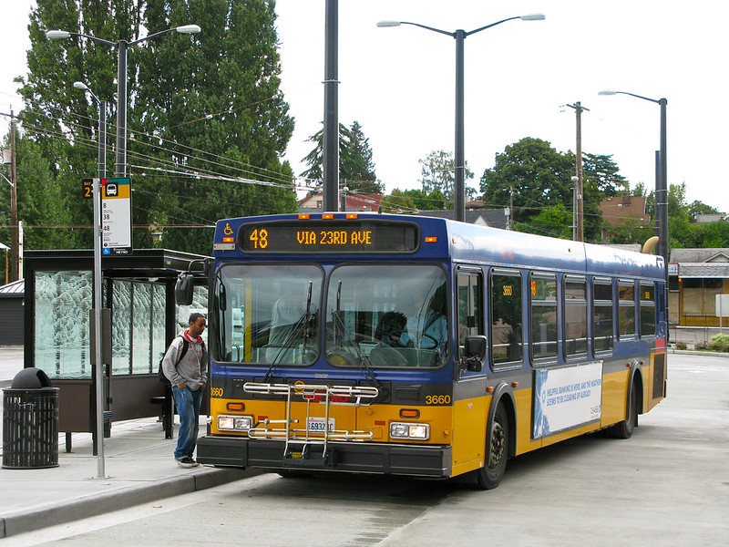 A Black man begins to board a King County Metro Route 48 bus after waiting at a bus shelter