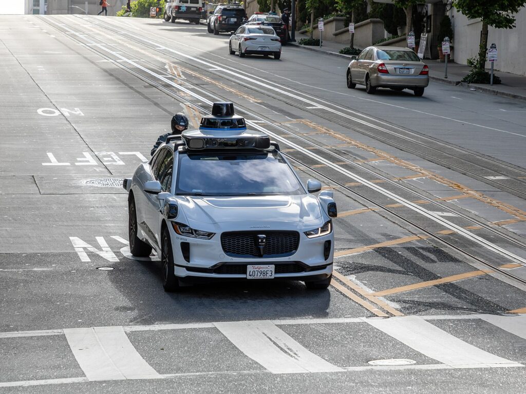 A car rests just before a crosswalk on a wide roadway