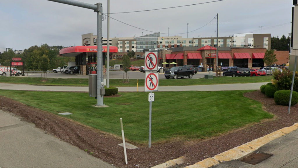 An image showing do not walk signs with a gas station complex in the background