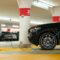 A black SUV is plugged into a charger at a numbered parking spot inside a parking garage.