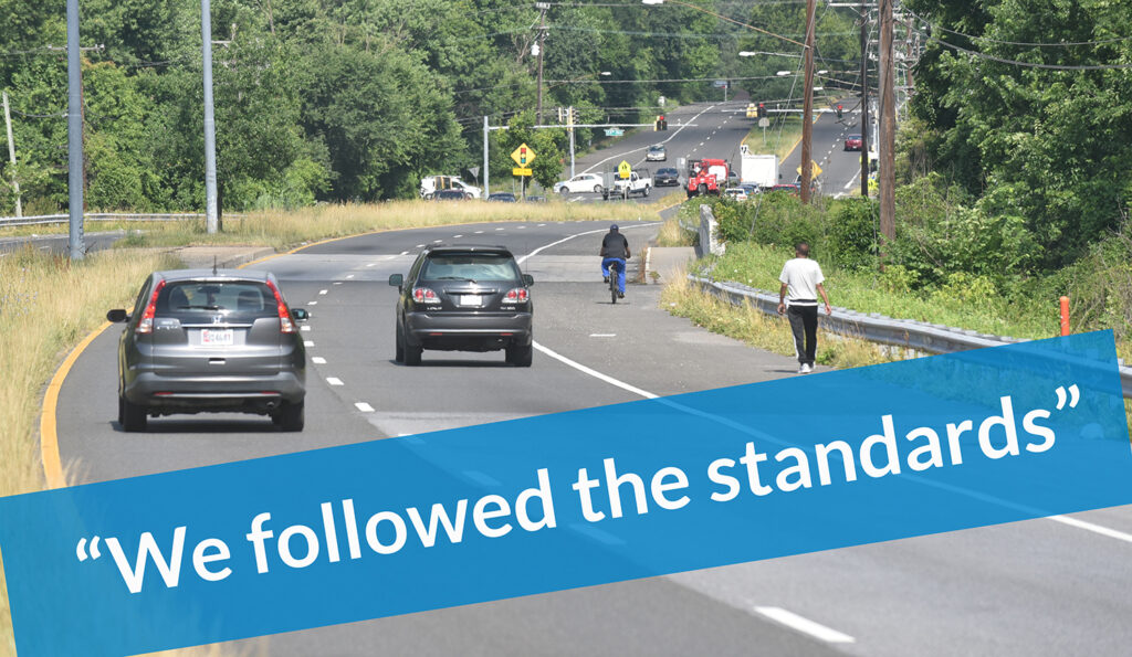 graphic - unsafe arterial street with people walking in shoulder, covered with a banner that says "we followed the standards"