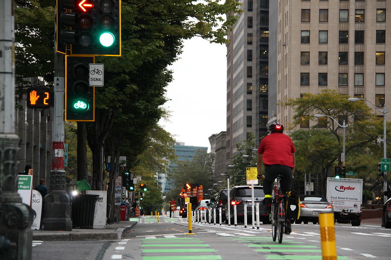 A cyclist crosses an intersection with the aid of a green bicycle crossing signal