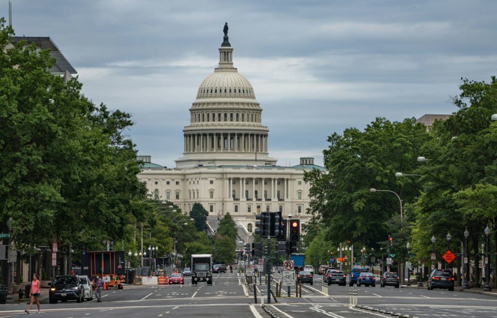 The U.S. Capitol from Pennsylvania Avenue, with people walking and driving on the road in the foreground