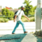 A man in jeans and a white t-shirt walks along the side of a wide, sunny street