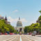 Photograph of a street facing the U.S. Capitol with bike lanes down the middle and pedestrians utilizing a crosswalk