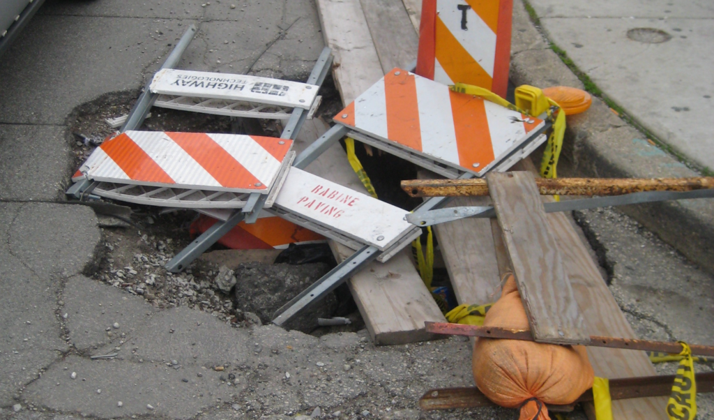 A pothole filled with caution signs