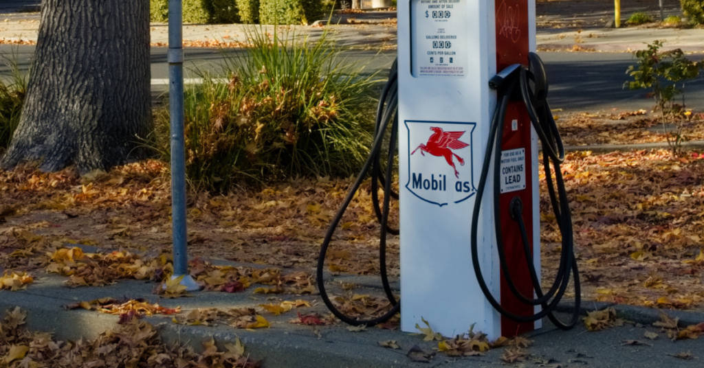 Two EV charging plugs rest on either side of a retrofitted gas pump bearing a faded label