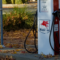 Two EV charging plugs rest on either side of a retrofitted gas pump bearing a faded label