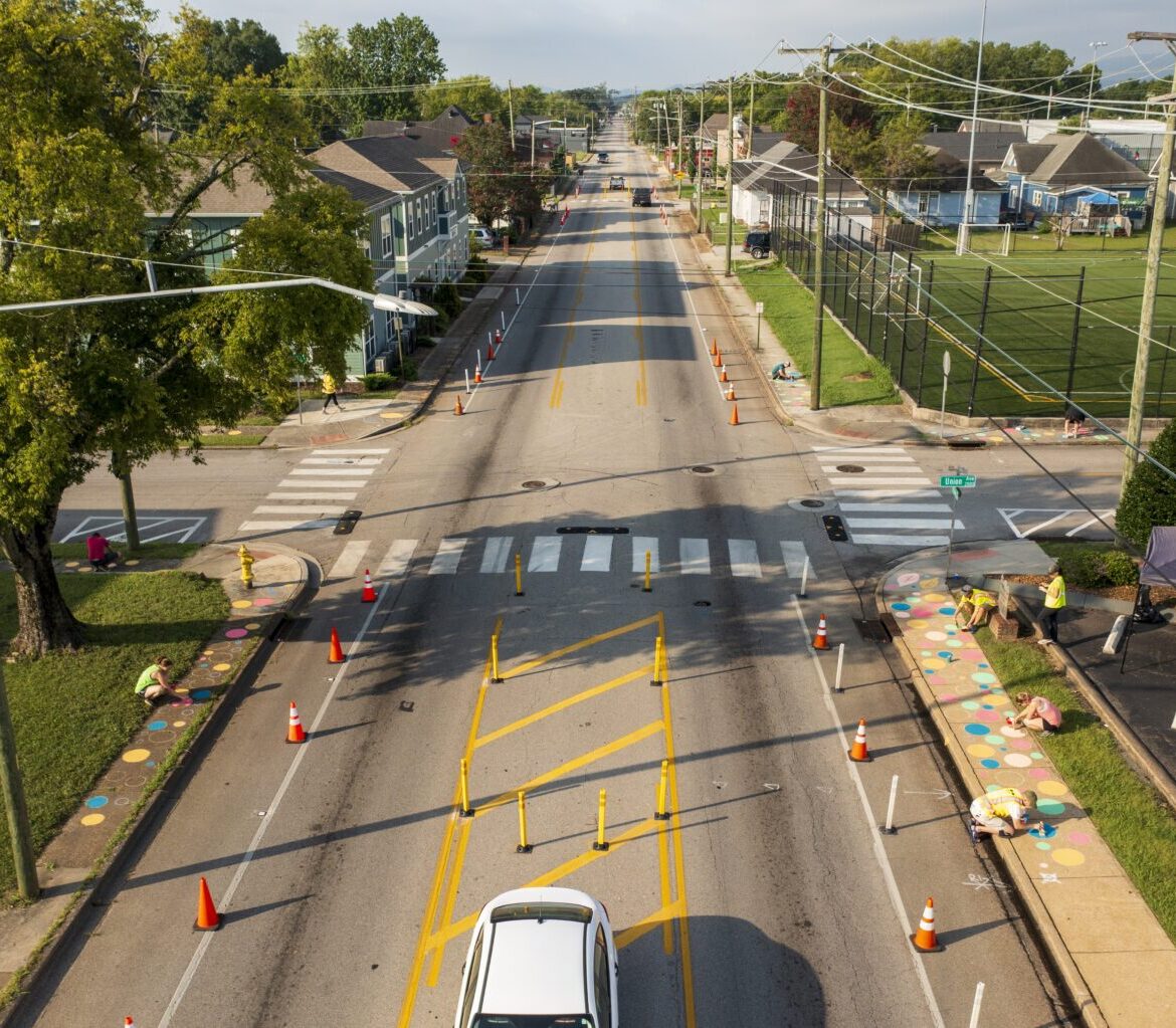 People add art to sidewalks along a quick build demonstration project complete with a flex post delineated bike lane and clearly marked crosswalk