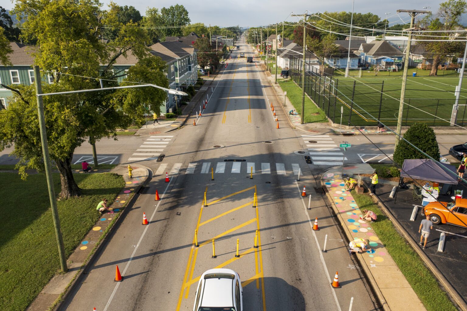 People add art to sidewalks along a quick build demonstration project complete with a flex post delineated bike lane and clearly marked crosswalk