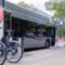 An electric Central Ohio bus arrives at a stop with a nearby bikeshare station