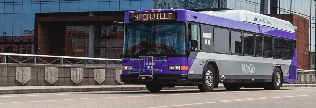 A purple WeGo Nashville bus travels down a city street