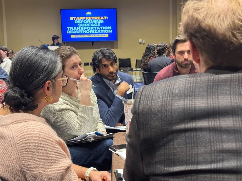 Group of people seated at a table in discussion during Transportation for America Congressional staffer retreat.